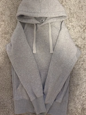 Ljusgrå hoodie med huva XS russemerch - Ljusgrå hoodie med klassisk huva och dragsnören. Hoodien har en stor magficka och ribbade muddar vid ärmslut och nederkant. Tillverkad i mjukt sweatshirtmaterial som är perfekt för chill dagar. Enkel och stilren design utan tryck.