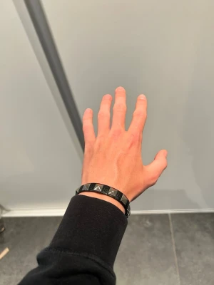 Valentino armband  - Snyggt svart armband med blanka pyramidformade nitar justerbar storlek