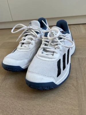 Adidas gympaskor strl 36 - Vita och blåa adidas gympaskor i storlek 36. Helt perfekt skick. Skickas samma dag som köp