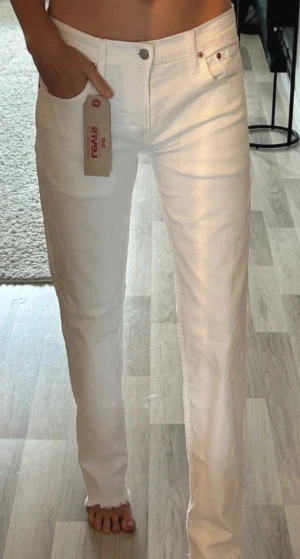 Vita raka jeans från Levi's - Säljer ett par vita jeans från Levi's med rak passform och råa kanter vid bensluten. Klassisk femficksmodell med knappgylf och bälteshällor. Perfekta för dig som gillar en clean och stilren look. Helt nya lappen kvar. Ny pris: 999kr