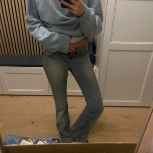 Blå bootcut jeans med låg midja - Snygga blå jeans med bootcut och låg midja. Jeansen har klassisk femficksdesign och är tillverkade i mjukt denimtyg. de har en lätt tvättad look 