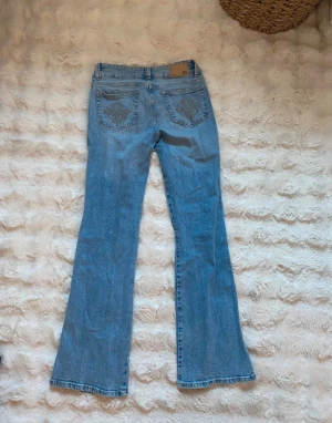Lager157 ljusblå bootcut jeans S - Säljer ett par Lager157 jeans i ljusblå tvätt med klassisk bootcut passform. Jeansen har snygga broderade detaljer på bakfickorna. Aldrig använda, full längd.