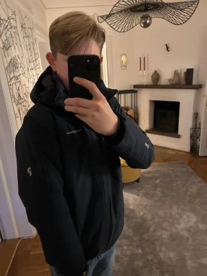 Mörkblå skidjacka Peak Performance - Snygg mörkblå skidjacka från Peak Performance med huva och dragkedja hela vägen. Jackan har diskreta loggor på bröstet och ärmen, samt praktiska fickor med dragkedja. Perfekt för dig som gillar stilren och funktionell design, eller bara vill ha en fett skidjacka till vintern👍 hör av er vid frågor😃