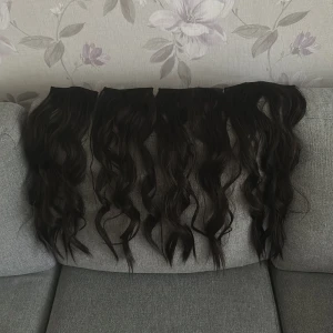Svart lockigt löshår med clips - Säljer ett set med svart, vågigt löshår med clips. Perfekt för dig som vill ha längre och fylligare hår på nolltid. Håret är mörkt och har naturliga lockar, enkelt att sätta i och ta ur. Passar till att skapa en cool och trendig look. Testat vid ett tillfälle 