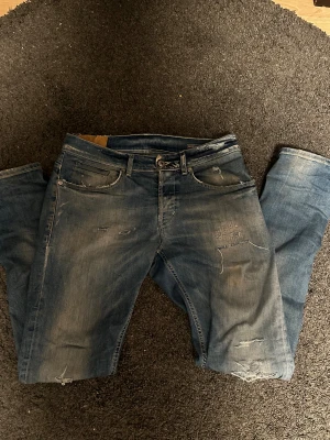 Dondup jeans - Säljer ett par blå dondup jeans med slitningar och riktigt snygga slitningar på både fram- och baksida. Jeansen har ljusare tvätt och sitter väldigt bra, pris kan gå ner vid snabb affär