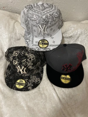 Broderi Keps  - Säljer ett gäng feta kepsar: New York Yankees från New Era med olika mönster, DC Shoes i helsvart, Tapout med döskalle och guldtryck samt en Leader med glittriga döskallar och strass. Färgerna är svart, grå, vit och guld, med broderade och tryckta detaljer. Perfekt för dig som vill sticka ut. 135kr/st , 