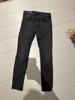 Replay svarta slim jeans - Svarta jeans från Replay med slim passform och klassisk femficksdesign. Jeansen har mörk tvätt, smal siluett och metallknapp med Replay-logga. Materialet är stretchigt jeans och midjan är normal. Perfekt för dig som gillar stilrena och tajta jeans.