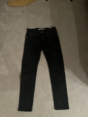 Svarta  jeans Calvin Klein W30 L32 - Svarta jeans från Calvin Klein Jeans i slim fit med klassisk femficksdesign och silverfärgade detaljer. Snyggt CK-märke på fickan och logga på linningen. Jeansen är tillverkade i stretchig bomull för en bekväm passform. Bara använt dem 2 gånger
