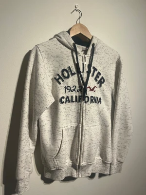 Hollister Zip Hoodie - Hej! Säljer nu denna väldigt snygga Hollister Zip Hoodien.  Storlek S Small   Färg: Grå & Vit Skick: Mycket gott   Skickas spårbart eller hämtas upp efter överenskommelse. Vid intresse – hör gärna av dig.  Skriv vid frågor eller ifall du vill ha fler bilder:) 