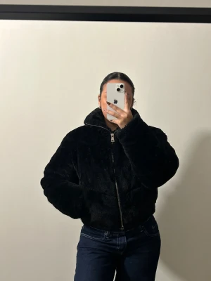 Svart teddyjacka från Pull&Bear - Mysig svart teddyjacka från Pull&Bear med hög krage och dragkedja framtill. Jackan är croppad, supervarm och snygg. I bra skick, skriv om flera bilder önskas 🥰