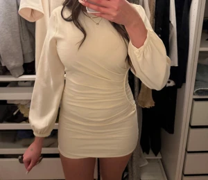 Ljus kort klänning med puffärm - Superfin ljus miniklänning med långa puffärmar och rynkdetalj i sidan.  Litet sömsläpp i sömnen bak (sista bilden). Endast använd 1 gång☺️ nypris 199kr