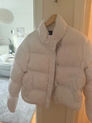 Vit pufferjacka från FB Sister - Säljer en vit pufferjacka från FB Sister i storlek M. Jackan har hög krage, stora fickor med knappstängning och dragkedja framtill. Perfekt för kalla dagar och har en riktigt snygg, puffig look som är trendig just nu.