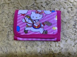 Barn plånböcker med motiv - Tre färgglada plånböcker med motiv av Hello Kitty och Peppa Pig. Alla har en rosa bas med glittriga detaljer och kantband i olika nyanser av rosa. Plånböckerna är tillverkade i syntetmaterial och har roliga tryck med ballonger, stjärnor och djur. Perfekt för att förvara kort och småpengar. 55kr/st , helt ny 