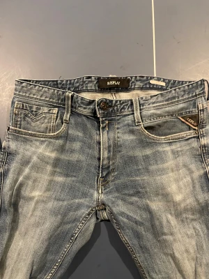 Replay ljusblå jeans med slitningar - ‼️Black Week Pris Endast 349 kr‼️Säljer ett par snygga ljusblå Replay Anbass jeans med klassisk femficksdesign och diskreta slitningar. Jeansen har slim passform och raka ben, med Replay-logga på fickan och bak på linningen. Perfekta för en avslappnad stil. 