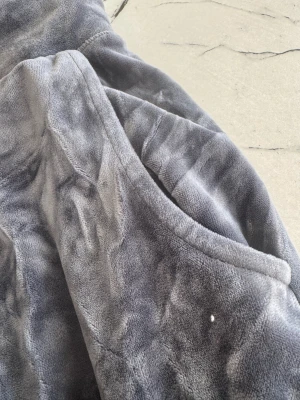 Grå mjukisbyxor med gul snörning - Säljer ett par grå mjukisbyxor i supermjuk fleece med gul snörning i midjan. Byxorna har normal passform och sidofickor, perfekta för chill hemma eller häng med kompisar. Materialet är lent och har en snygg, lite glansig yta.