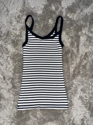 Randig linnetopp från H&M, svart/vit - Säljer en snygg randig linnetopp från H&M i storlek S. Toppen har svarta och vita horisontella ränder, smala axelband och är ribbad i materialet. Perfekt att ha under stickat🤍🖤