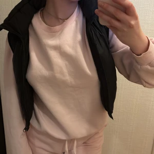 Svart dunväst med dragkedja - Svart dunväst med quiltad design och dragkedja framtill. Västen har en klassisk, lite puffig form och är perfekt att slänga över en hoodie. Enkel och stilren look som funkar till många outfits. Passar dig som gillar streetwear och vill ha något bekvämt och snyggt.