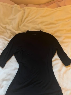 Svart topp från Gina Tricot - Svart tight strechig topp med trekvartsärm från Gina Tricot i storlek M. 