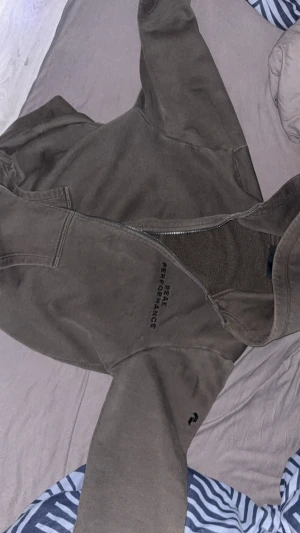 Peak Performance hoodie - Mysig mörkgrön fleecejacka från Peak Performance med dragkedja framtill och broderad logga på bröstet. Jackan har hög krage och är perfekt för kyliga dagar. Materialet är mjukt och värmande fleece, och modellen är klassisk med långa ärmar.