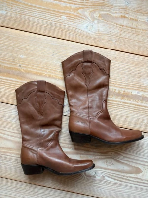Bruna cowboy boots i skinn - Snygga boots i äkta läder!! Varsamt använda och motsvarar storlek 39 (står 40 men de är små i storleken). Nypris är cirka 2000kr