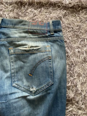 Dondup  - Säljer ett par blå dondup i storlek 33 jeans med snygga slitningar och tvättad look. Jeansen har klassisk femficksdesign, normal passform och raka ben. Tillverkade i slitstarkt bomullsmaterial och perfekta för en avslappnad stil.
