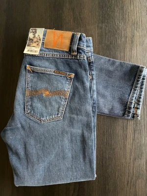Nudie Jeans W29 L30 Lean Dean - Helt oanvända schyssta sprillans nya blå jeans från Nudie Jeans med klassisk femficksdesign & orangea sömmar(NYPRIS‼️1600kr). Jeansen har en rak passform & är tillverkade i slitstarkt bomullsjeansmaterial. Perfekta för en avslappnad & stilren look. ‼️Kom med frågor om du är osäker. 😁Jag är villig att sänka priset.