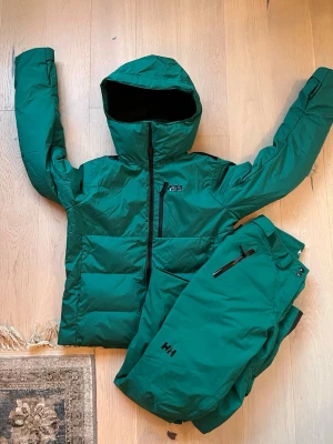 Grön skidjacka och byxor från Helly Hansen - Säljer ett grönt skid ställ från Helly Hansen. Aldrig använda pga. Fel storlek men etiketterna är av så kunde inte returnera. Nypris : 6600kr Byxorna har svarta detaljer vid benslut och dragkedjor på fickorna. Perfekta för vintern och i skidbacken. Materialet är slitstarkt och vattenavvisande. Jackan är i storlek Medium och byxorna i storlek Large. Säljer helst tillsammans som ett helt skid set men kan diskutera om enskilda produkter om det önskas