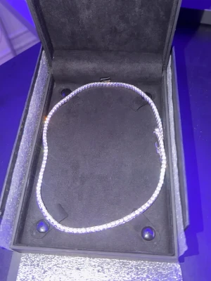 Silverfärgat tennis-halsband Kejsar - Säljer ett stilrent tennis-halsband från Kejsar i silverfärg med gnistrande stenar runt hela kedjan. Halsbandet har en klassisk, elegant design och levereras i original ask. Perfekt för alla hjärtans dag present 
