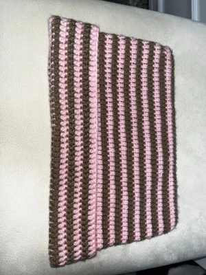 Randig virkad katt-örat mössa brun och rosa - Säljer en handgjord virkad mössa med bruna och ljusrosa ränder. Mössan har en klassisk tubform och är ribbstickad för extra stretch och passform. Perfekt för dig som vill ha en unik accessoar med retrovibbar. Materialet känns mjukt och varmt, perfekt för kyliga dagar.