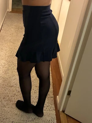 Mörkblå kjol Tommy Jeans  - Supersnygg mörkblå kortkjol från Tommy Jeans i storlek S. Kjolen har en figurnära passform och volangkant nedtill. Diskret dragkedja i sidan och klassisk Tommy-logga broderad vid linningen. 