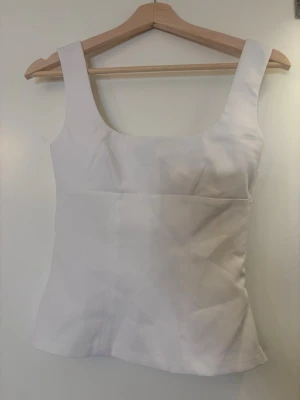 Vit topp - Säljer denna söta topp från H&M då den är för liten, storlek xs men skulle nog ksk kunna passa s🥰 Tror det är ngn bronzer fläck någonstans men går bort i tvätten, aldrig använd!! Kom med prisförslag! ❣️