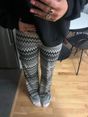 Mönstrade byxor från Alice by Belle jhoes - Säljer ett par riktigt snygga byxor från Alice by Belle Shoes med zigzag-mönster i svart, grått och vitt. Byxorna har en relaxed passform och är tillverkade i ett mjukt, stretchigt material. Perfekta för dig som vill sticka ut med coola mönster.