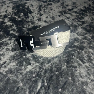 J.Lindeberg Bälte - Tja! Säljer nu detta galet feta J.Lindeberg Bältet i Nyskick, with tags (10/10)! Size: ONE SIZE/95, Fits= Samma som alla flätade bälten. Helt nytt aldrig använt. Vit/Beige färg, riktigt schysst och metall spänne av högsta kvalite! Made in Italy!🇮🇹 Hör av dig vid minsta fundering eller fråga!🌟