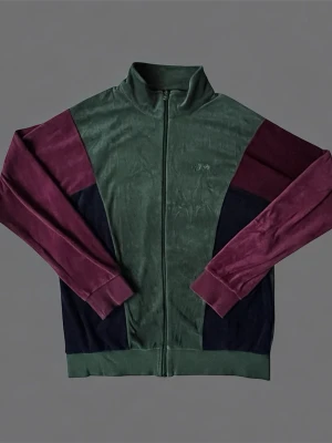 Äkta! Grön och vinröd ziptröja från Stüssy - Snygg ziptröja från Stussy i mjuk velour med färgblock i grönt, vinrött och mörkblått. Tröjan har hög krage, hel dragkedja och diskret broderad logga på bröstet. Perfekt för en avslappnad streetwear-look.