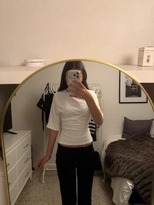 Populär Vit topp med knyt i ryggen från Nelly - Snygg vit topp med kort ärm och knyt i ryggen. Modellen är croppad och har en enkel, stilren design som passar till många outfits. 