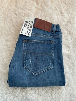 Blå skinny jeans med slitningar - Snygga blå skinny jeans med slitningar på båda benen. Jeansen har en mörkblå tvätt och normal midja.  Storlek W29 L32.