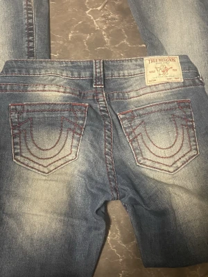 True Religion blå jeans med röd söm - Jättefina true religion jeans med röda sömmar. Jeansen är i jättefint skick bortsett från att det är lite slitet längst ner på byxbenen (bild 5). Jag är 165 cm lång och jeansen passar mig bra längden. Priset kan diskuteras! 💕