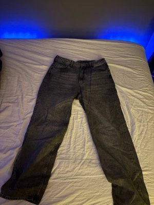 Mörkgrå raka jeans - Snygga mörkgrå jeans med rak passform och klassisk femficksdesign. Jeansen har normal midja och är tillverkade i ett robust jeanstyg som passar perfekt till en avslappnad stil. Inga synliga loggor eller detaljer utöver det klassiska snittet.