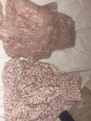 2 för 1 volangkjol - Supersöt kort kjol i ljusrosa med blommigt mönster och volang. Kjolen har en bred, smockad midja som ger en bekväm och snygg passform. Perfekt för vår och sommar, lätt och luftig i materialet.