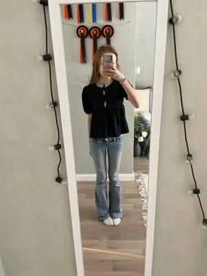 Marinblå blus med knyt från 157 - Supersöt marinblå blus från 157 med korta puffärmar och knytning framtill vid halsen. Modellen är lite lös och har en lätt volang nedtill. Perfekt att styla med jeans eller kjol för en chill look.