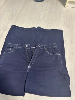Mörkblå wide jeans med kontrastsömmar H&M -  Klassisk fick modell med knapp och dragkedja fram. Perfekta för dig som gillar en avslappnad och trendig stil.
