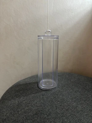 Transparent burk/Pojemnik na kosmetyki - Praktisk transparent burk i plast med lock och rund knopp. Perfekt för förvaring av bomullspads, tops eller andra små skönhetsprodukter. Cylindrisk form och enkel design som passar in i de flesta badrum eller sminkbord.