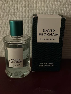 David Beckham Classic Blue parfym - David Beckham Classic Blue Eau de Toilette, 50 ml. Flaskan är genomskinlig med en stilren vit etikett och blågrön metallkork. Förpackningen är mörkblå med diskret mönster och vit etikett framtill. En fräsch och maskulin doft. Priset ej hugget i sten