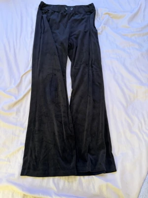Svarta mjukisbyxor i sammet - Säljer ett par svarta mjukisbyxor i mjuk sammet med bred resår i midjan och dragsko. Byxorna har raka, vida ben och en bakficka. Perfekta för chill dagar eller när du vill vara extra bekväm.