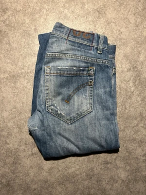 Dondup George W30 - Snygga ljusblå jeans från Dondup med klassisk femficksdesign och slitna detaljer på benen. Jeansen har raka ben och normal passform, perfekt för en avslappnad stil. Tillverkade i mjukt bomullstyg för skön känsla. W30 lagade i skreve hos skräddare.