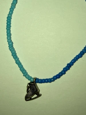 Blått pärlarmband med skridsoberlock - Handgjort armband av mig med små pärlor i två nyanser av blått och en silverfärgad skridsoberlock. Armbandet har justerbar kedja i metall och är perfekt för dig som gillar sportiga detaljer och färgglada accessoarer. Frakt 22-100kr. Kontakta mig om du har frågor eller vill köpa.