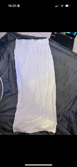 Vit långkjol i mjukt material - Säljer en enkel och stilren vit långkjol med rak passform. Kjolen är gjord i ett mjukt och lätt material som känns skönt mot huden. Perfekt för dig som gillar minimalistisk stil och vill ha en kjol som är lätt att matcha med olika toppar.