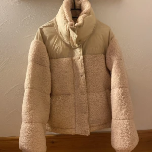 Beige teddyjacka från Sixth June S - Säljer en beige teddyjacka från Sixth June i storlek S. Jackan har pufferstil, hög krage och dragkedja med tryckknappar. Utsidan är i mjuk teddy och ovandelen i slät polyester. Perfekt för kalla dagar och riktigt snygg streetwear-vibe.