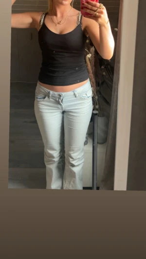 Ljusblå bootcut jeans låg midja - Säljer ett par ljusblå jeans med bootcut passform och låg midja. Jeansen har klassisk femficksdesign, knapp och dragkedja framtill samt ljus tvätt. Materialet är jeans och de har en avslappnad, lite loose fit över benen.