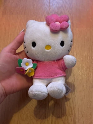 Hello Kitty Gosedjur - Supersöt liten hello kitty. Vad mer kan man säga?! Hon vill hem till dig genast och ge dig blommorna hon håller! Hon är så exalterad att hon till och med har en blomma vid örat!